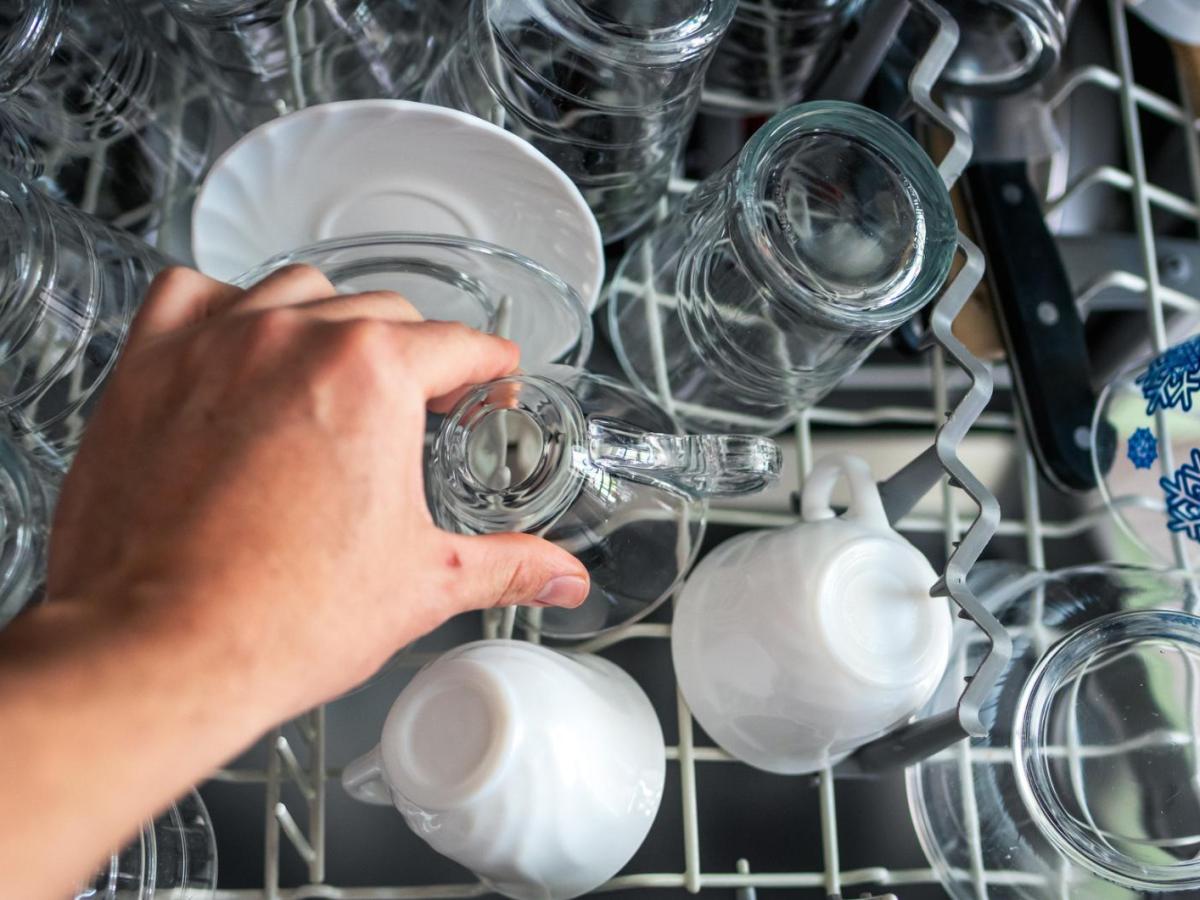 Person räumt Geschirr aus einer Spülmaschine.