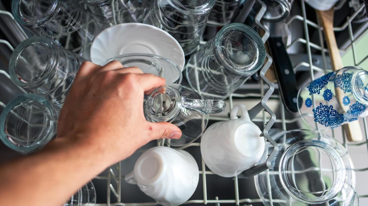 Person räumt Geschirr aus einer Spülmaschine.