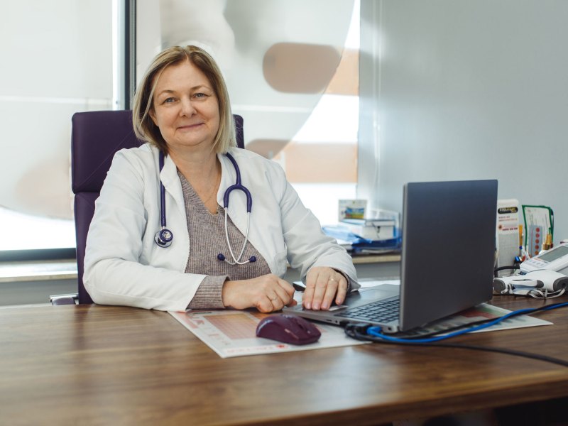 Ärztin sitzt an ihrem Schribtisch.