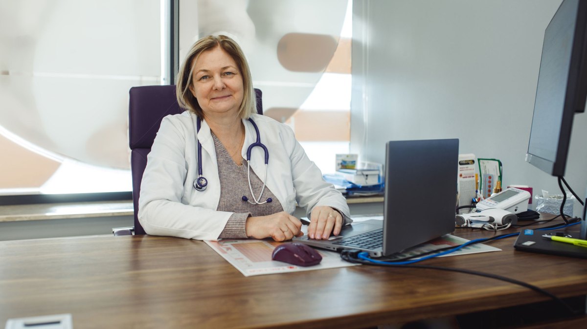 Ärztin sitzt an ihrem Schribtisch.