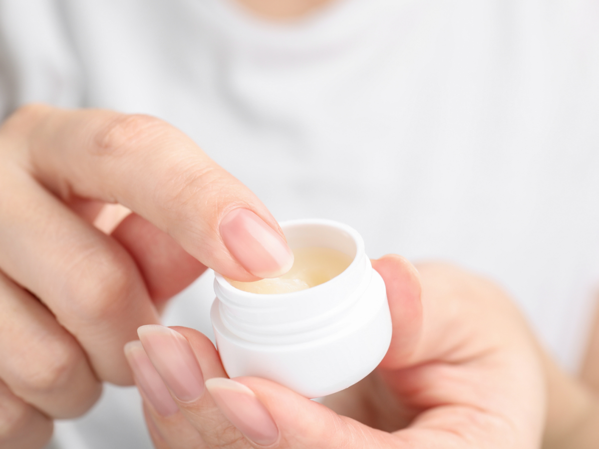 Eine Frauenhand nimmt etwas Vaseline mit dem Finger aus der Dose