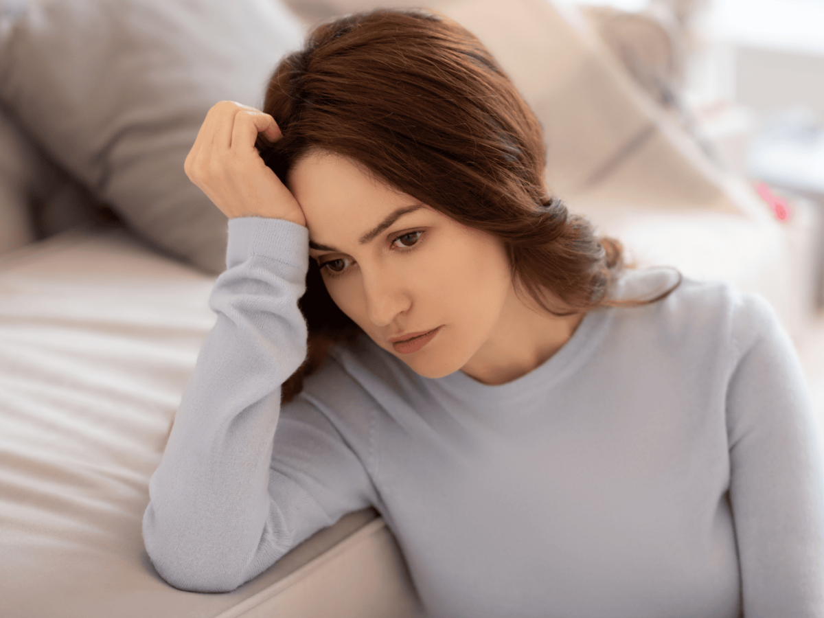 Frau mit Kopf auf Arm abgest&uuml;tzt schaut traurig