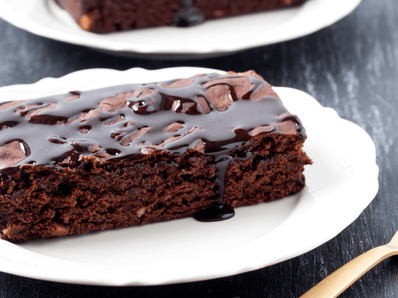 Ein Stück Schokokuchen mit Glasur auf einem weißen Teller.