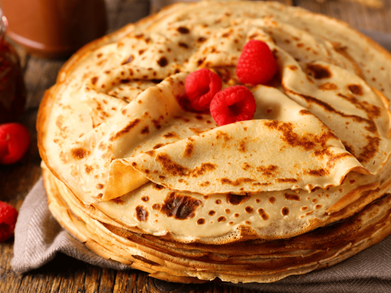 Ein großer Stapel dünner Pfannkuchen auf einem Holztisch.