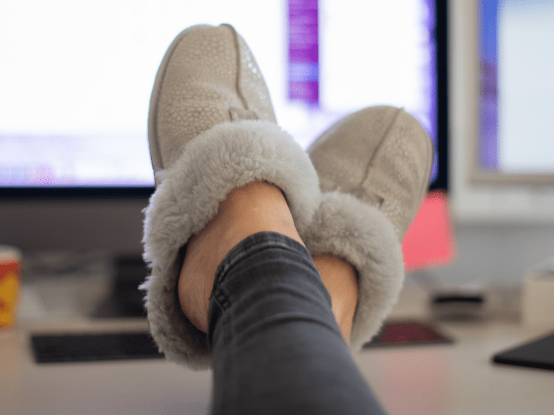 Füße mit Hausschuhen auf dem Schreibtisch im Homeoffice
