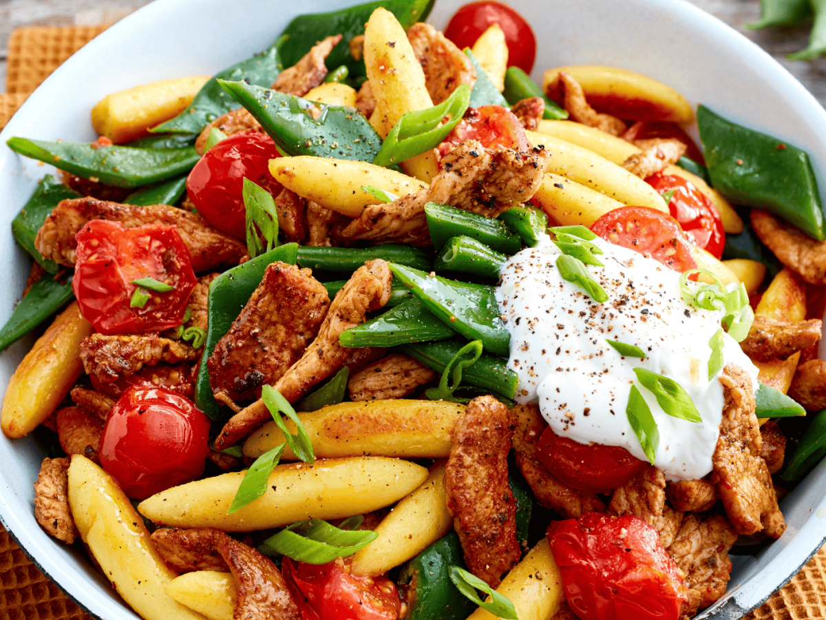 Gyros-Schupfnudel-Pfanne mit Tomaten und grünen Bohnen auf einem weißen Teller.