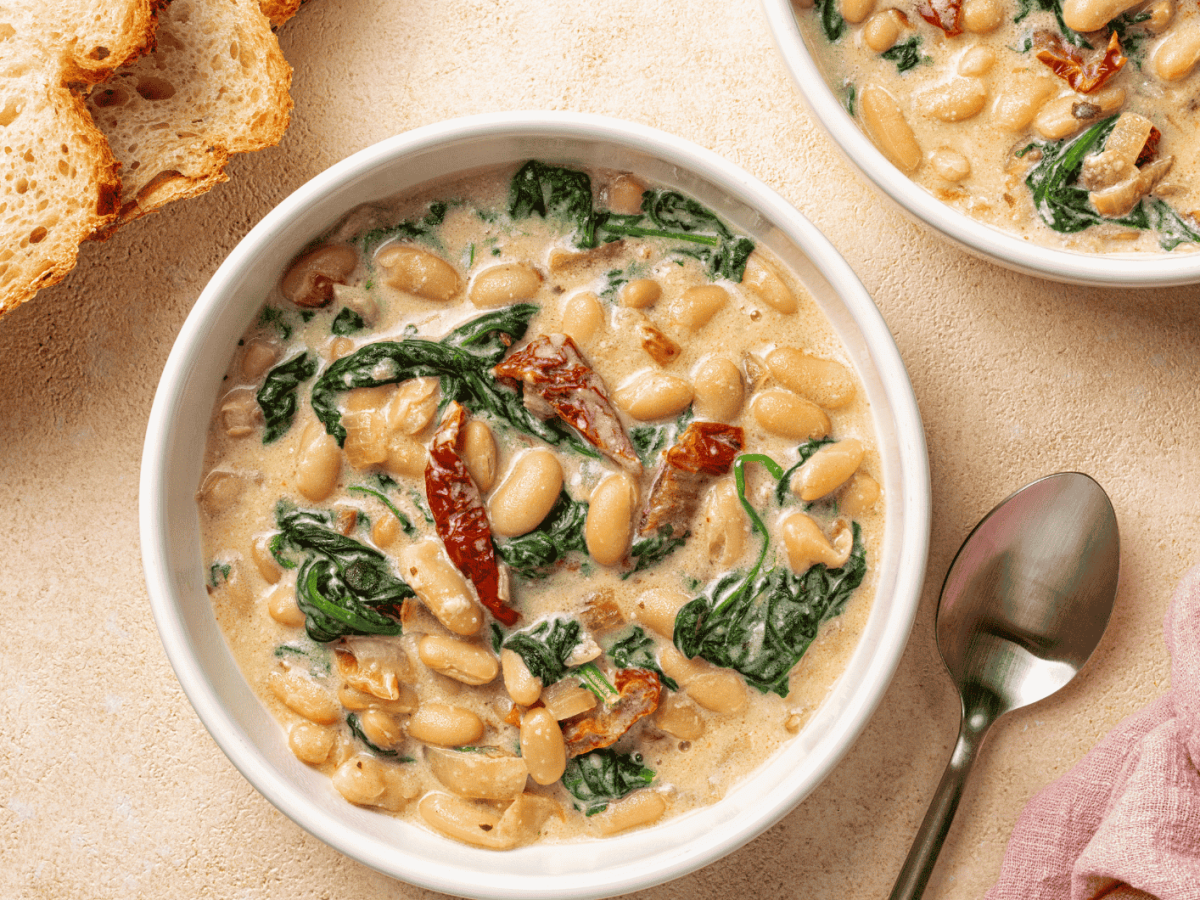 Toskanische Bohnensuppe mit Spinat und getrockneten Tomaten in einer weißen Schüssel.