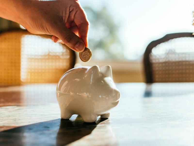 Frau wirft Geld in ein Sparschwein.