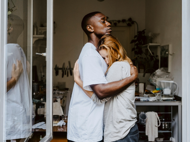 Ein Mann und eine Frau umarmen sich innig und schauen sorgenvoll