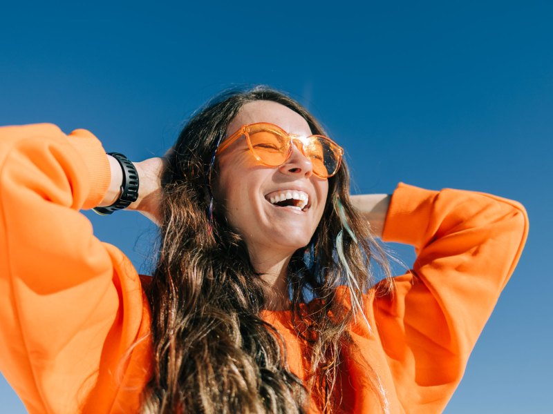 Frau in orangefarbenem Sweatshirt und Brille