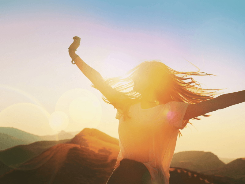 Frau mit ausgestreckten Armen dreht sich bei Sonnenschein