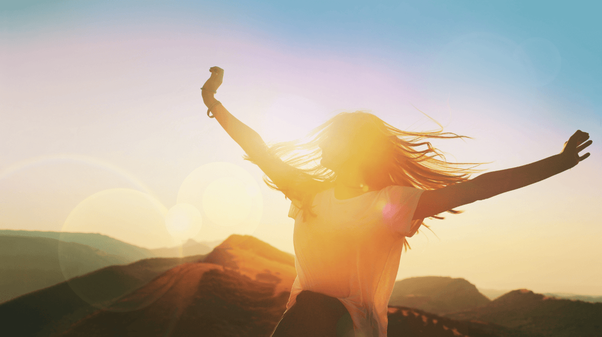 Frau mit ausgestreckten Armen dreht sich bei Sonnenschein