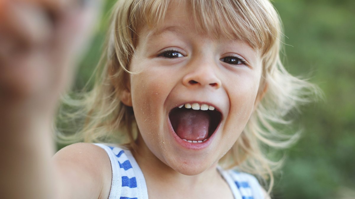 Close-up eines kleinen Jungen, der in die Kamera lacht.