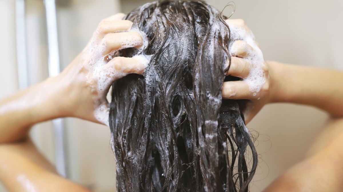 Frau wäscht sich unter der Dusche die Haare,