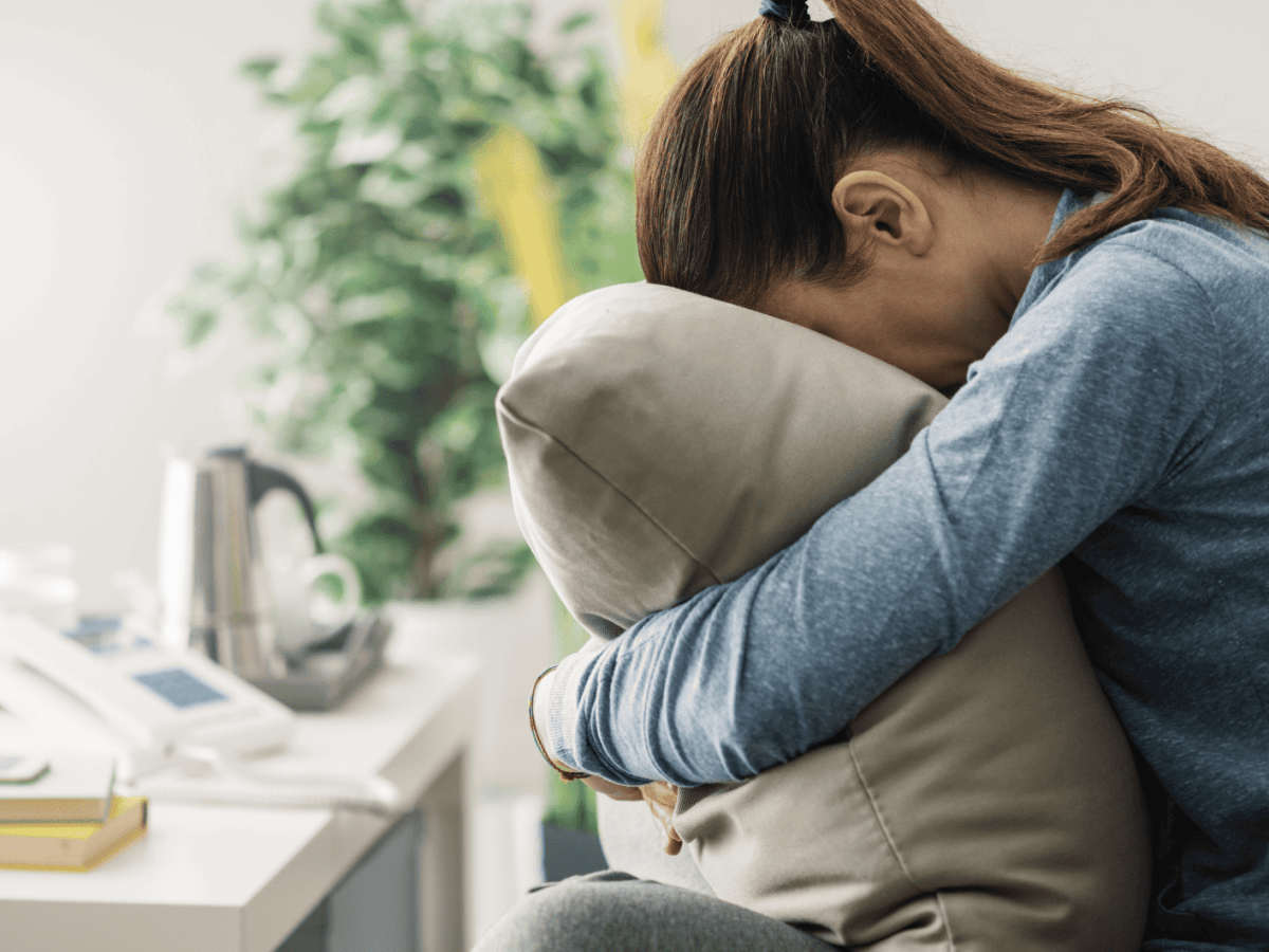 Frau auf dem Sofa dr&uuml;ckt ihr Gesicht frustriert in ein Kissen