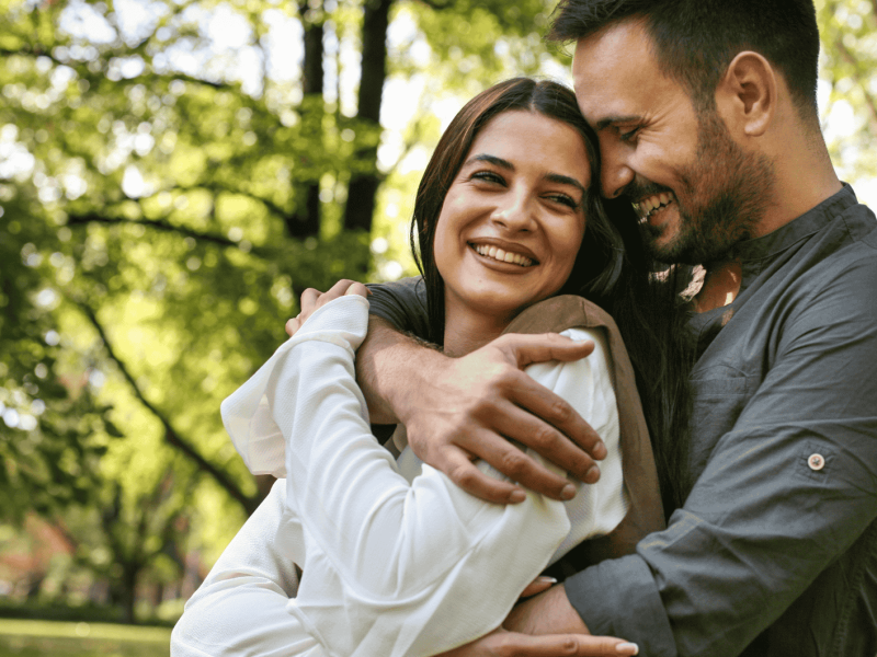 Mann umarmt Frau von hinten im Wald