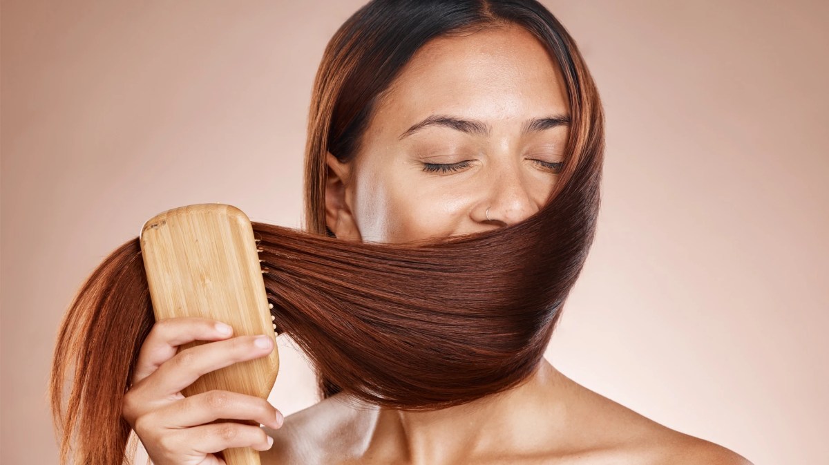 Frau, die ihre langen Haare vor die Nase hält und daran riecht.