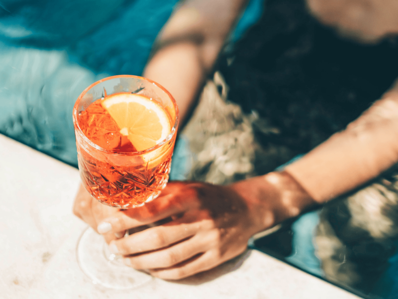 Schöne Frau trinkt Sommercocktail am Schwimmbad.
