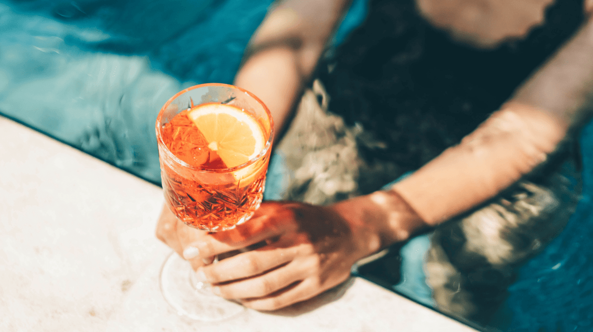 Schöne Frau trinkt Sommercocktail am Schwimmbad.