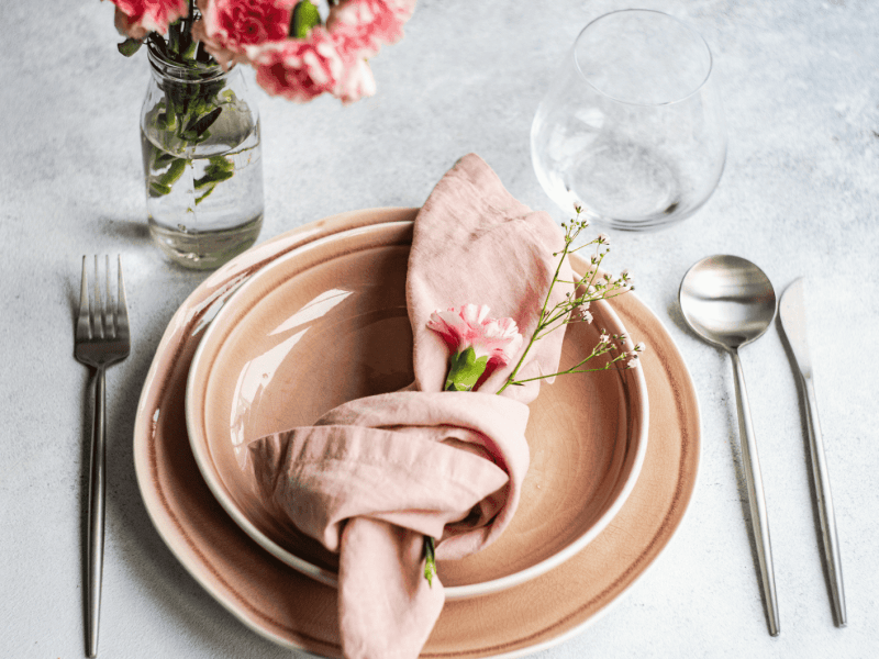 Rosa Geschirr auf grauem Tisch, mit rosa Serviette.