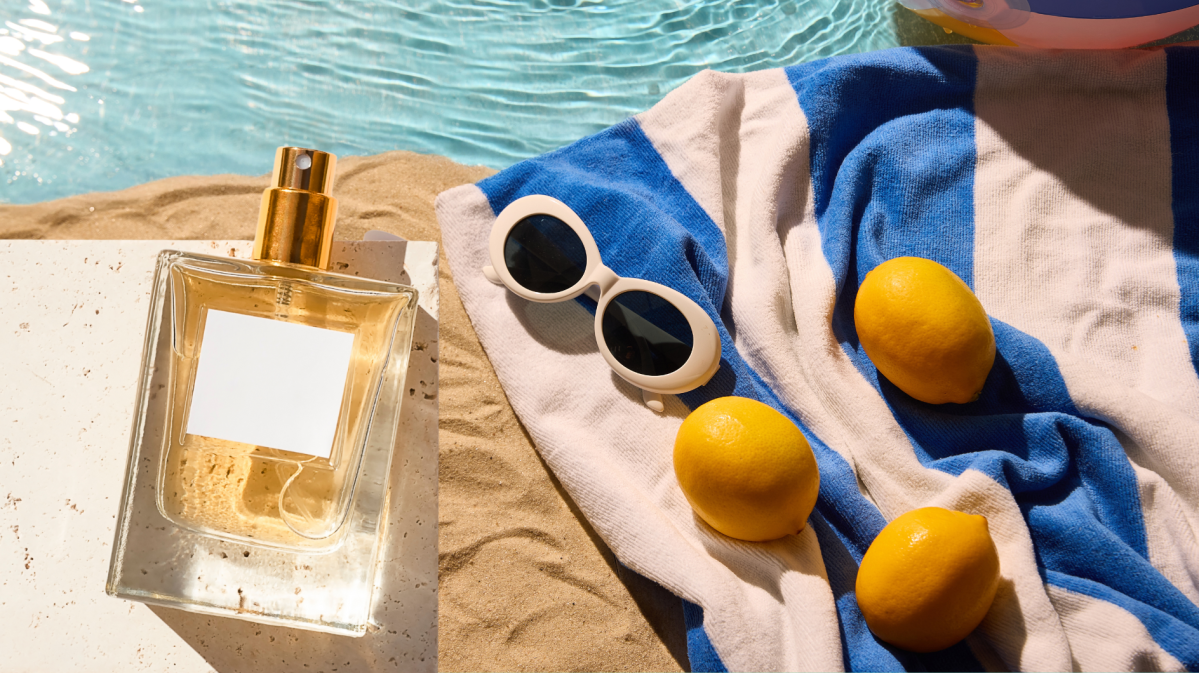 Parfum auf Sand mit Handtuch und Sonnenbrille