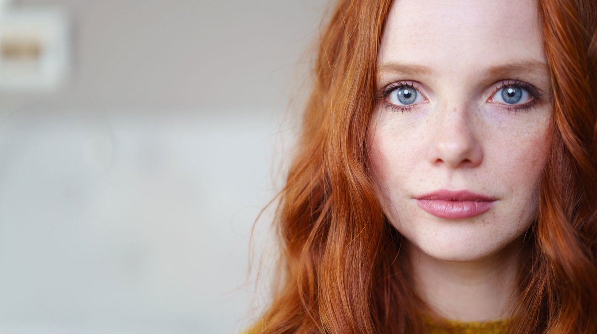 Frau mit roten Haaren schaut in die Kamera