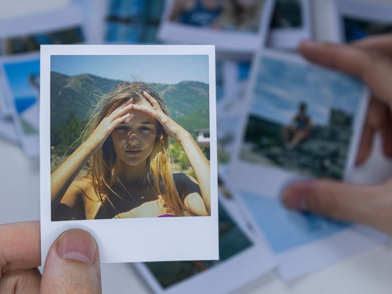 Frau hält ein Polaroidfoto von sich in den Händen