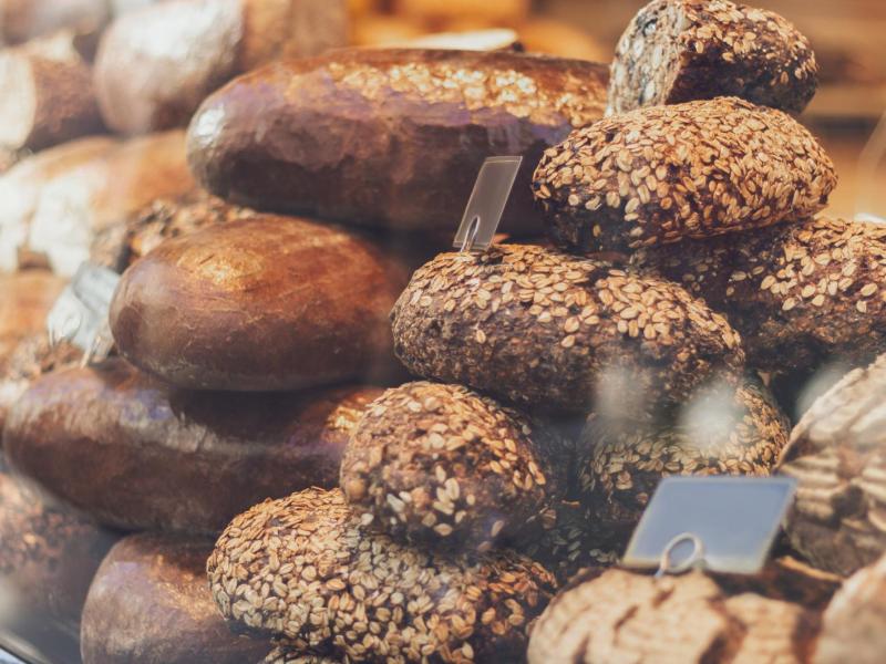 Brötchen liegen bei einem Bäcker hinter einer Glasscheibe aus.