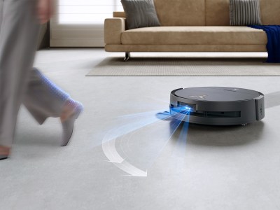 Dank AIVI 3D 3.0 Navigation erkennt der DEEBOT X9 PRO OMNI Hindernisse frühzeitig, plant seine Route intelligent und weicht dynamisch aus – für eine reibungslose und sichere Reinigung. Moderner Saugroboter erfasst einen vorbeilaufenden Menschen mit Sensoren und weicht präzise auf hellem Wohnzimmerteppich aus.