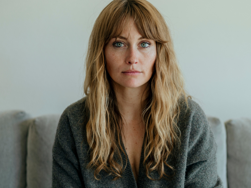 Frau mit langen blonden Haaren schaut ernst in die Kamera