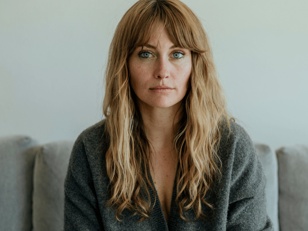 Frau mit langen blonden Haaren schaut ernst in die Kamera