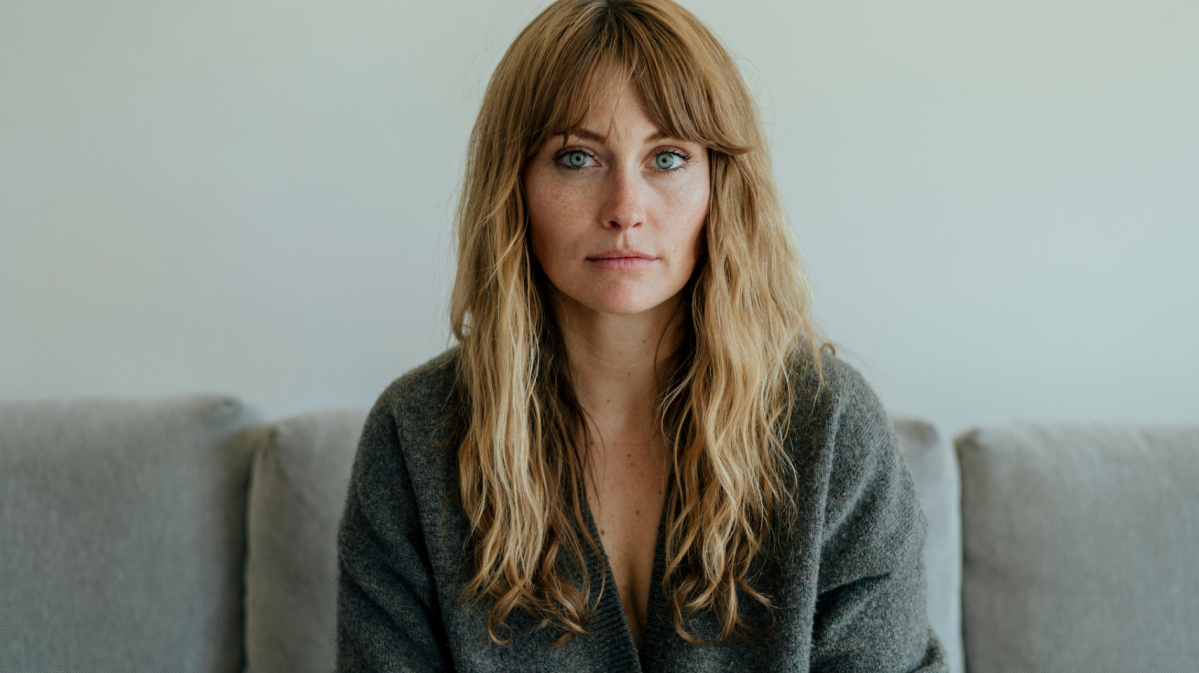 Frau mit langen blonden Haaren schaut ernst in die Kamera