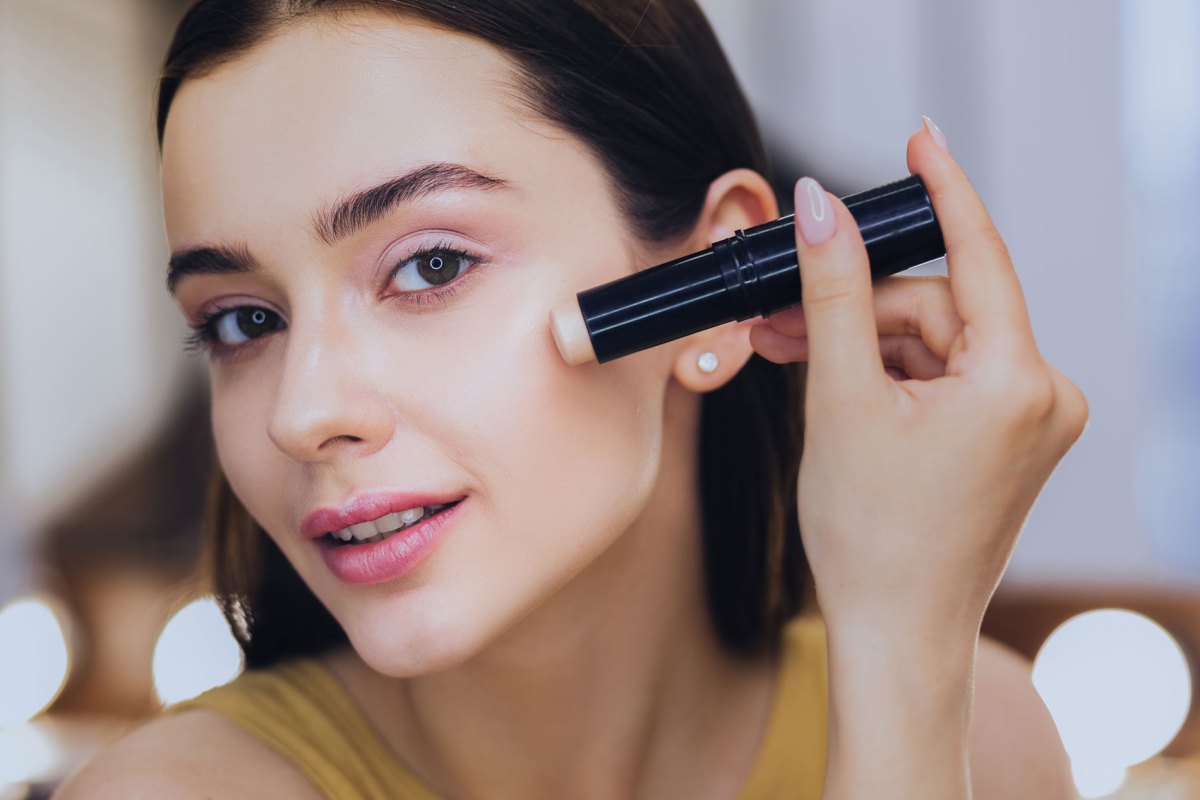 Frau, die mit einem Stift Make-up aufträgt.