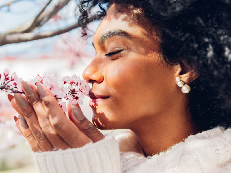 Frau, die an Kirschblüten schnuppert.