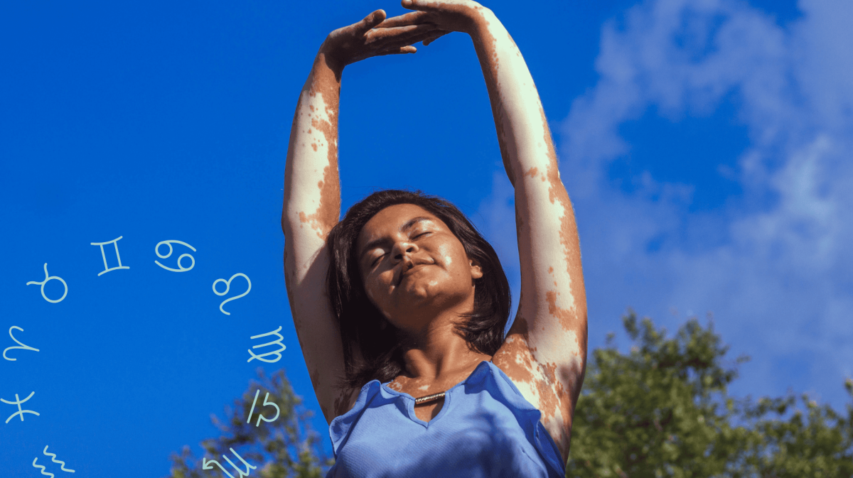 Frau mit blauem Oberteil streckt Arme in die Luft vor blauem Himmel