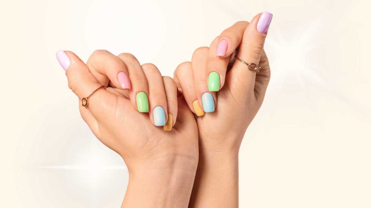 Bunt lackierte Fingernägel vor einem gelben Hintergrund