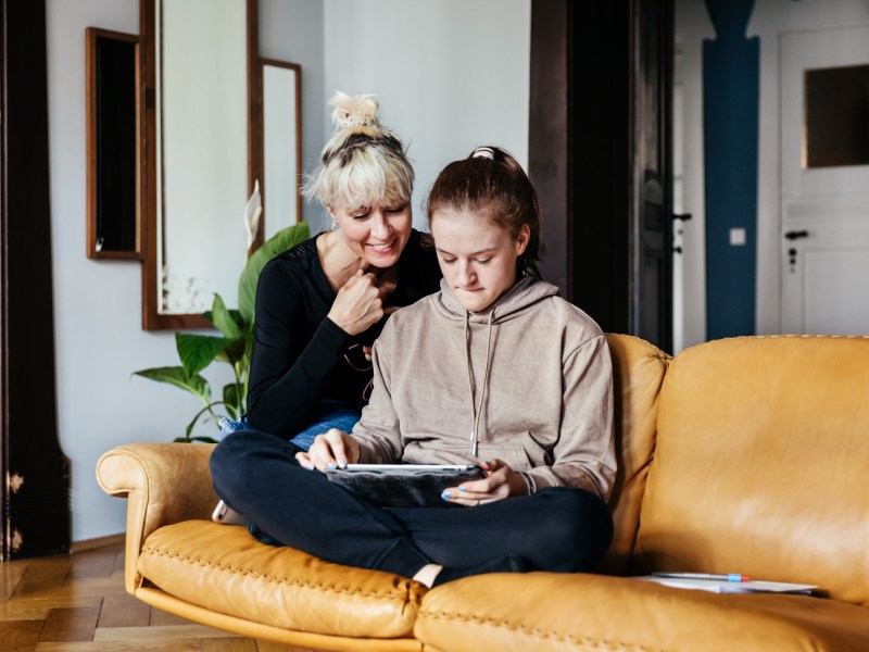 Helikopter-Eltern: Mädchen Teenager mit Mutter auf gelber Couch