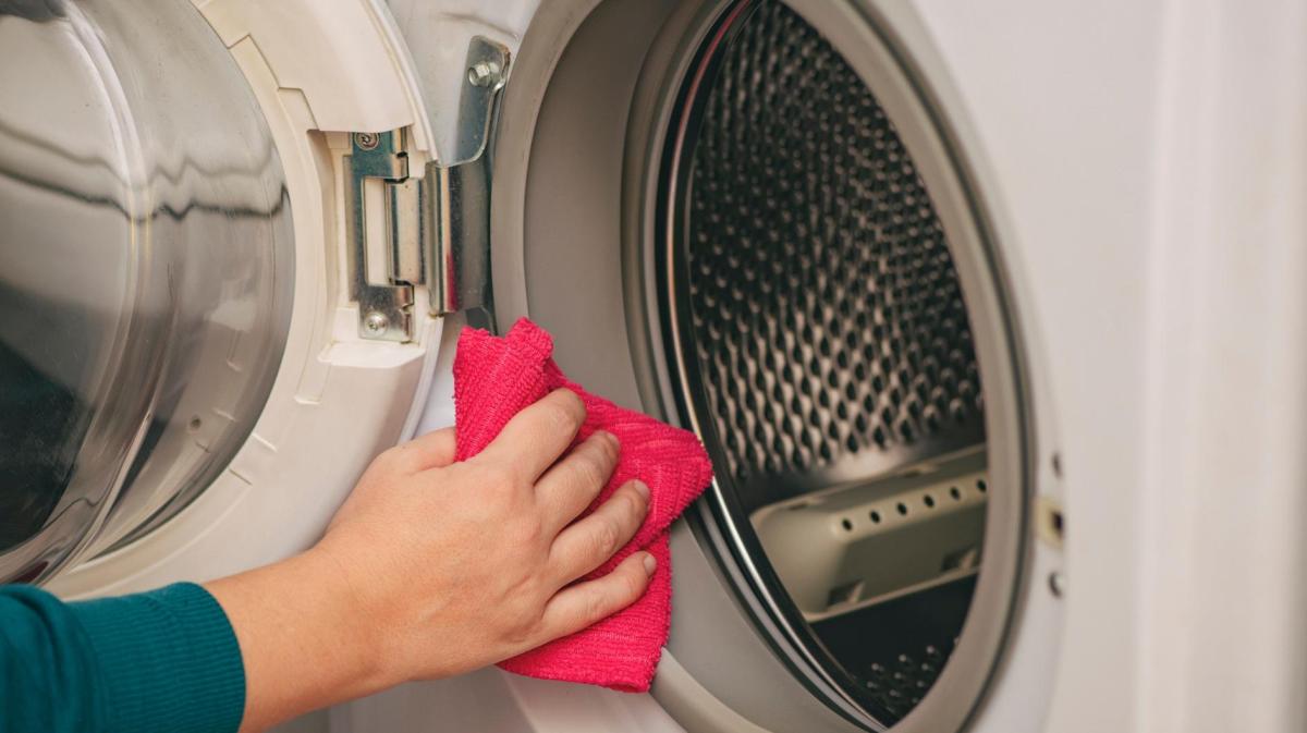 Frau wischt eine Waschmaschine ab.