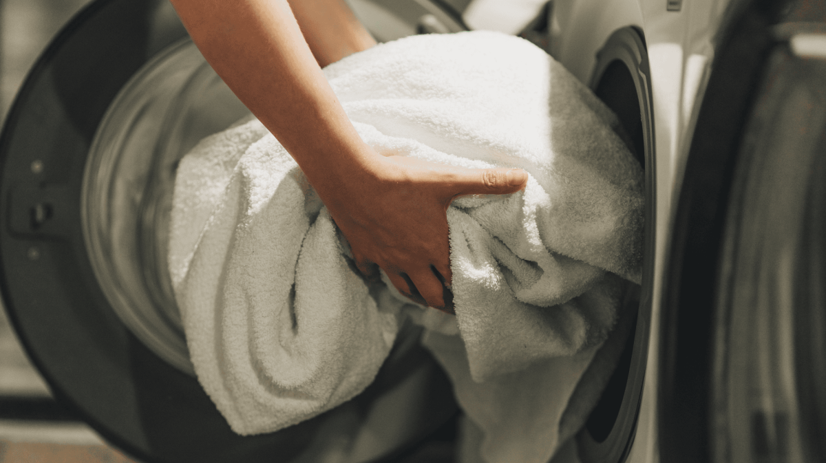 Person holt Wäsche aus dem Trockner