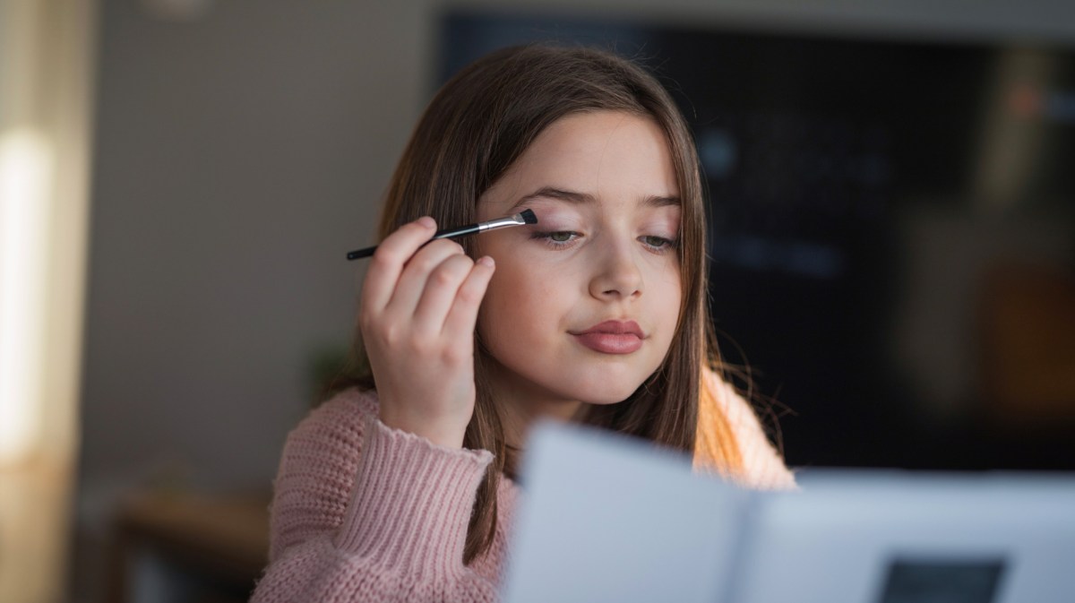 Junges Mädchen, das Lidschatten aufträgt.