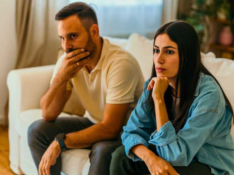 Paar sitzt nachdenklich auf der Couch.