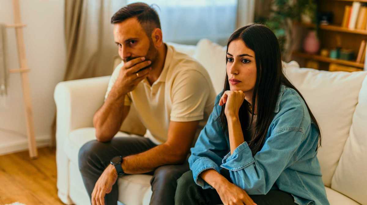 Paar sitzt nachdenklich auf der Couch.