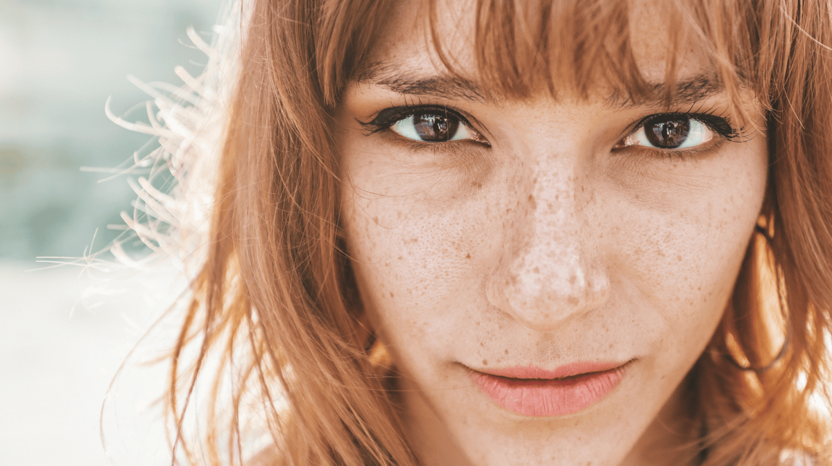 Junge Frau mit roten Haaren schaut direkt in die Kamera.
