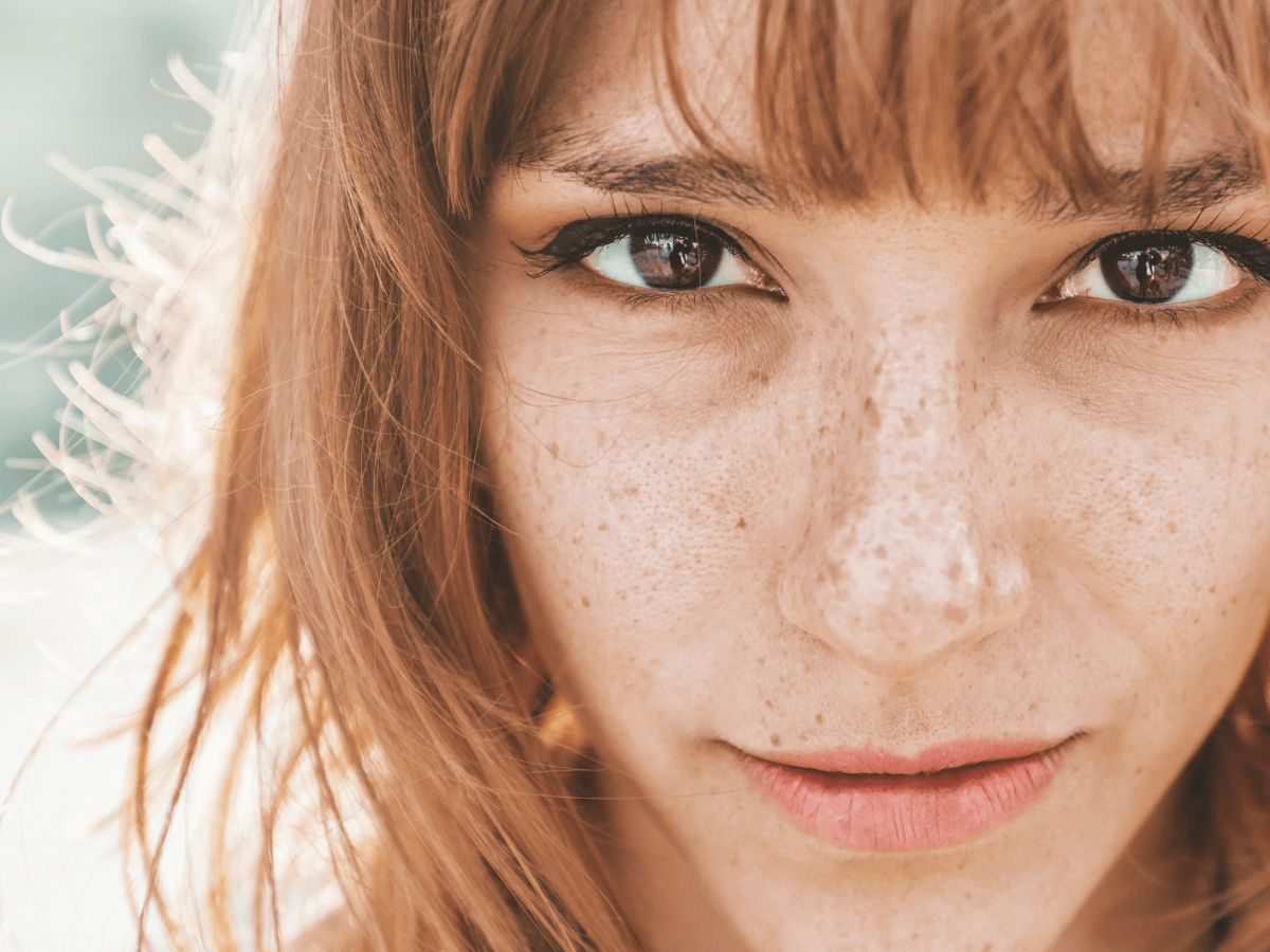 Junge Frau mit roten Haaren schaut direkt in die Kamera.