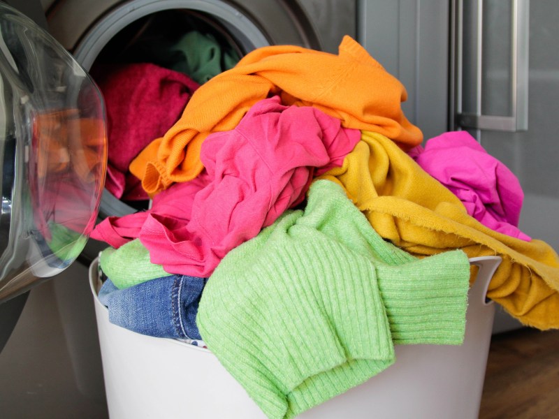 Wäschekorb mit Buntwäsche vor Waschmaschine