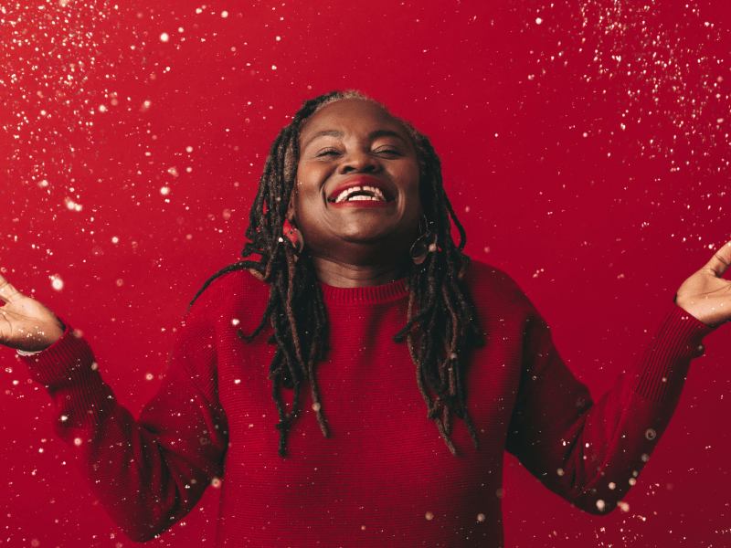 Fröhliche reife Frau, die mit Konfetti feiert