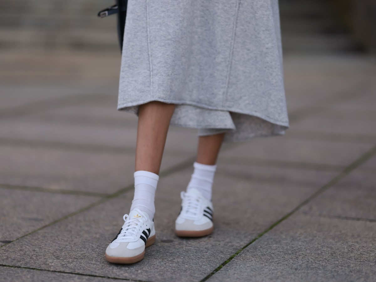 Nahaufnahme graues Wollstrickkleid, wei&szlig;e Baumwollsocken und wei&szlig;e Adidas-Leder-Samba-Sneaker.
