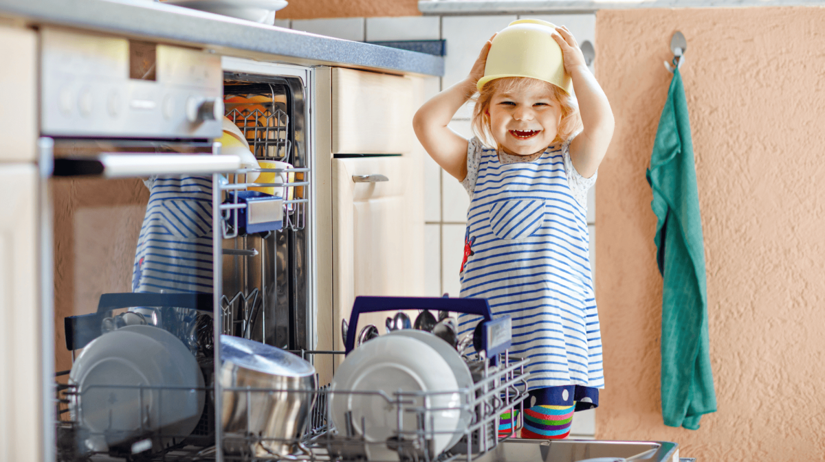 Kleines Kind steht vor geöffneter Spülmaschine.