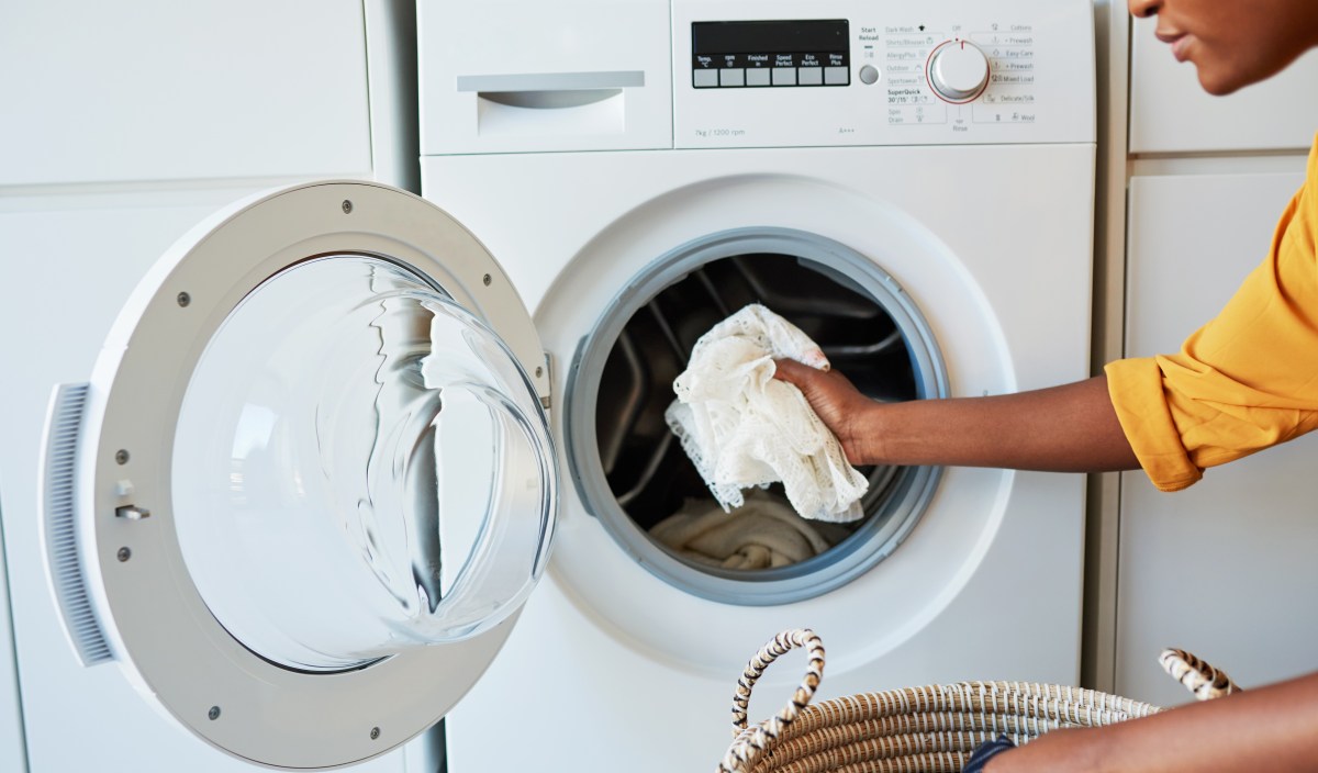 Frau legt weiße Wäsche in die Waschmaschine