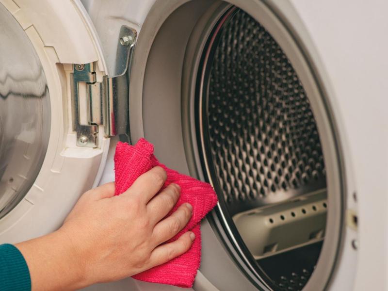 Frau wischt durch eine Waschmaschine.